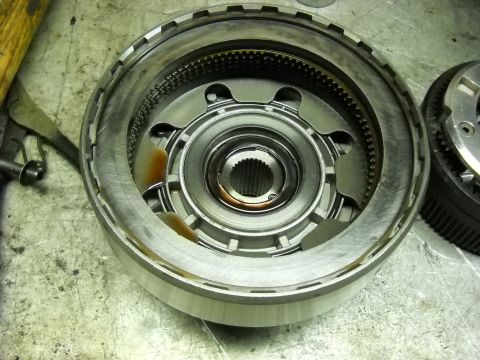 1993 Ford C-150 (Centurion Conversions) - Disassembled automatic transmission part on a workbench, showing internal gears and metal components.