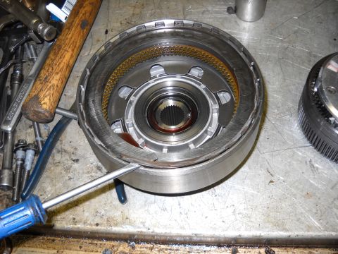 1993 Ford C-150 (Centurion Conversions) - A transmission component is being disassembled with tools on a workbench.
