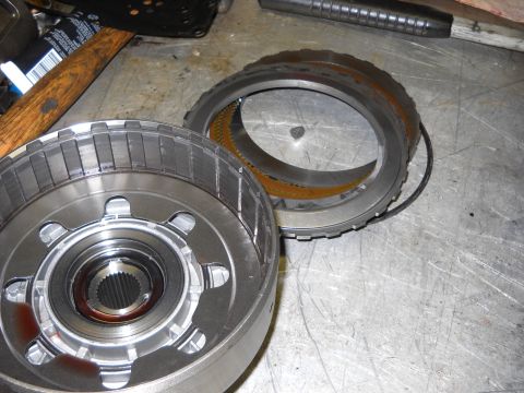 1993 Ford C-150 (Centurion Conversions) - Disassembled transmission components, including a drum and ring gear, are laid out on a workbench.