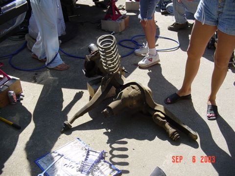1989 Ford Bronco - Vehicle suspension parts are laid out on the ground, possibly during a repair or disassembly process.