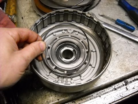 1993 Ford C-150 (Centurion Conversions) - A snap ring is being placed into a disassembled automatic transmission clutch pack on a workbench.