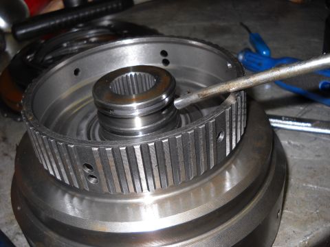 1993 Ford C-150 (Centurion Conversions) - A transmission drum and splined shaft are shown during a rebuild process, with a tool engaged on the drum's teeth.