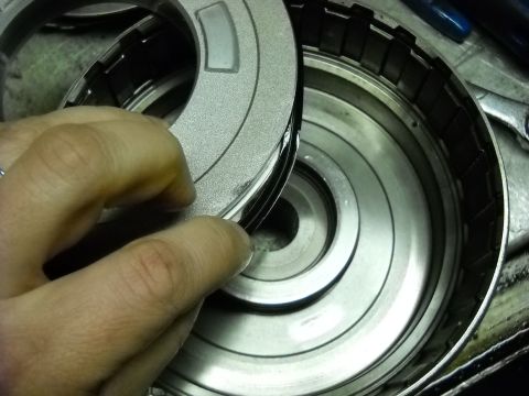 1993 Ford C-150 (Centurion Conversions) - A hand holds a metal clutch plate, examining it within a transmission drum.