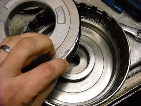 1993 Ford C-150 (Centurion Conversions) - Close-up of a hand holding a part of a transmission torque converter during a rebuild.