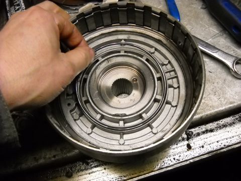1993 Ford C-150 (Centurion Conversions) - Close-up of a transmission torque converter part being held by a hand during a rebuild.