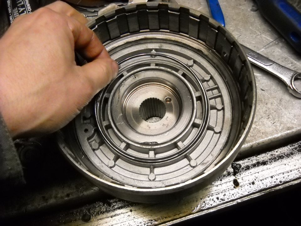 Hand holding a metal ring inside a disassembled transmission torque converter