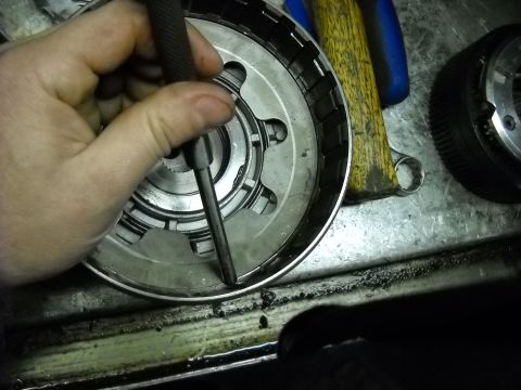 1993 Ford C-150 (Centurion Conversions) - Close-up of a mechanic's hand working on a transmission drum, with tools in the background.