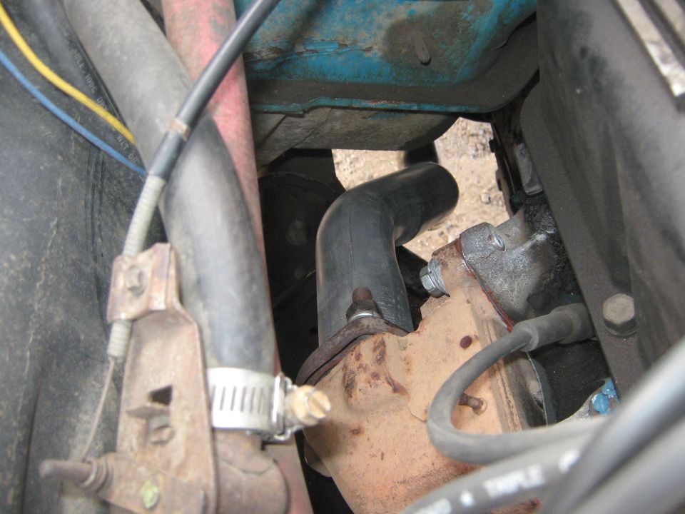 Close-up of engine components including hoses and exhaust manifold