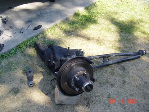 1989 Ford Bronco - Front axle assembly removed from vehicle, resting on grass with tools nearby.