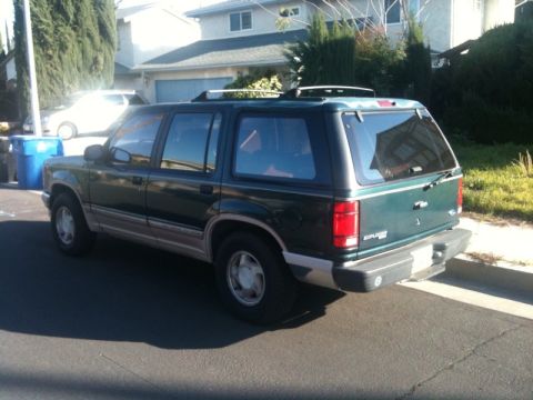 1993 Ford Taurus - This green SUV, identified as an Explorer, is seen from the rear 3/4 angle. The registry claims it is a 1993 Ford Taurus, but the body styl…