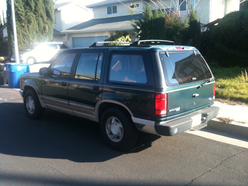 Green SUV, rear 3/4 view. Badge reads EXPLORER