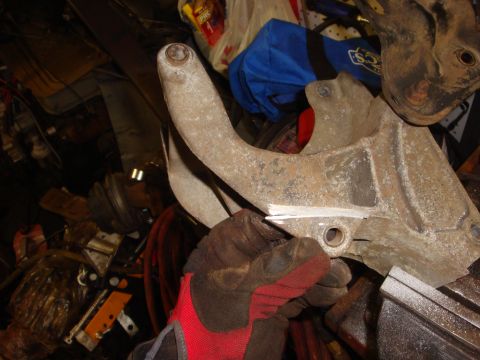 1989 Ford Bronco - A gloved hand holds a rusty alternator bracket, likely for a Ford Bronco swap.