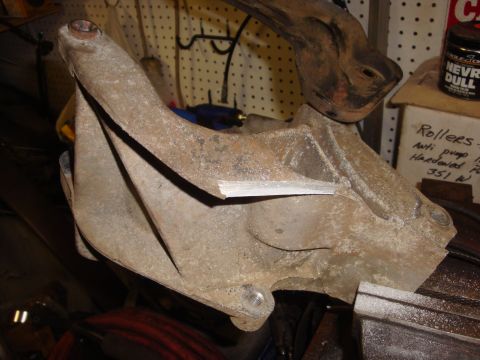 1989 Ford Bronco - Close-up of a rusty metal bracket, possibly for an engine component, with text visible on a nearby box.