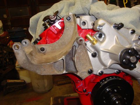 1989 Ford Bronco - Close-up view of an engine part, likely an alternator bracket, attached to a red-painted engine block.