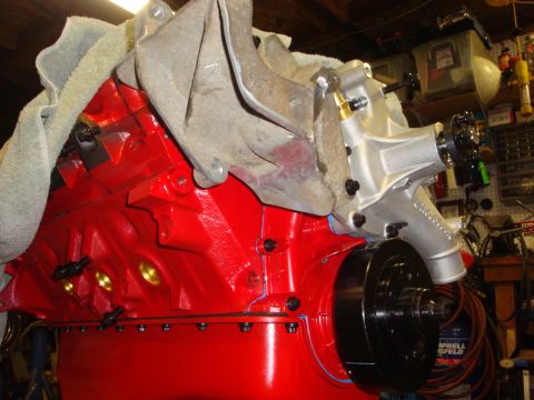 1989 Ford Bronco - Close-up view of a freshly painted red engine block a silver water pump and a black pulley.