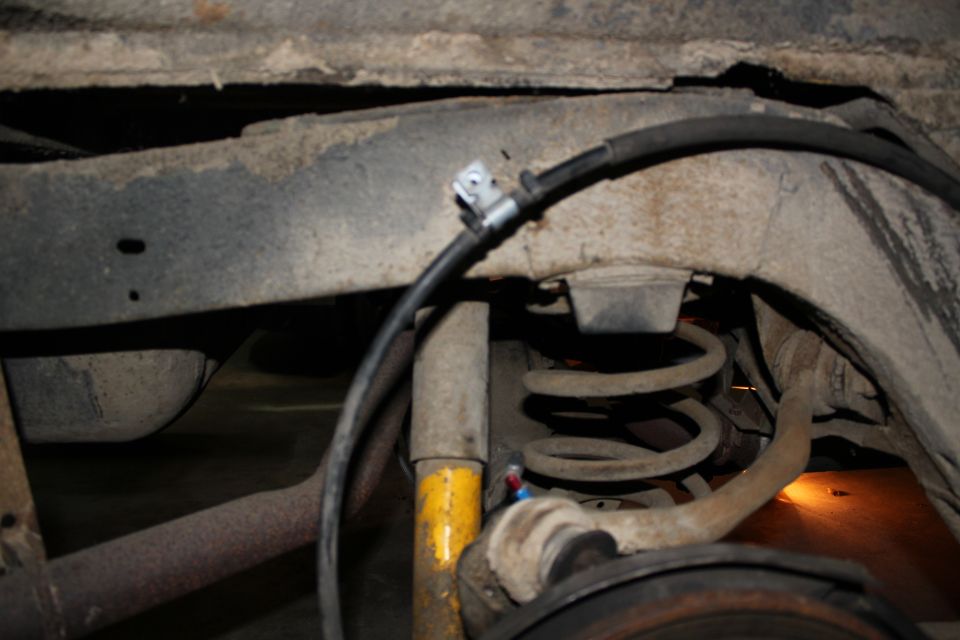Rear suspension coil spring and brake line under a vehicle