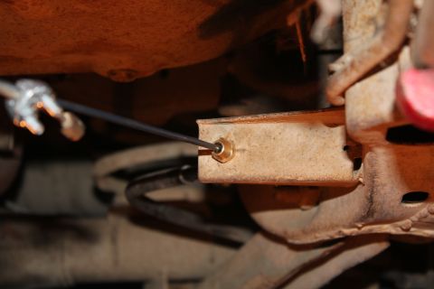 1972 Ford Ranchero - A close-up view of a bolt being secured to a vehicle's frame, showing rusty metal components.