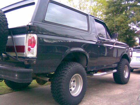 1991 Ford Bronco - This 1991 Ford Bronco is shown from a rear three-quarter angle, highlighting its lifted suspension and off-road tires.