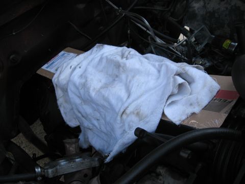1981 Ford Bronco - Engine bay partially covered by a towel, with a FEL-PRO parts box visible beneath.