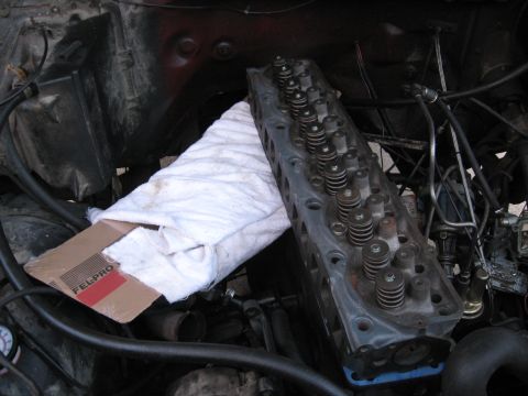 1981 Ford Bronco - Engine cylinder head removed from a vehicle, with a Fel-Pro box nearby.