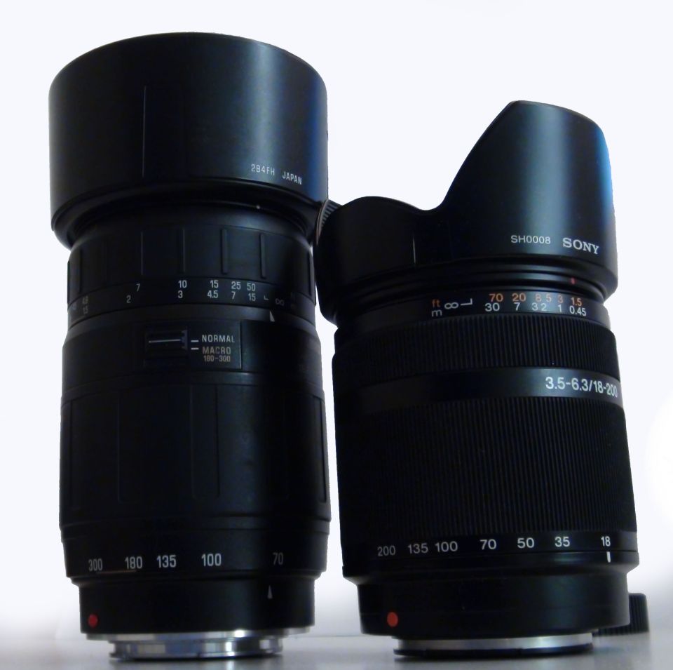 Two black camera lenses, one labeled Sony 3.5-6.3/18-200, with distance markings
