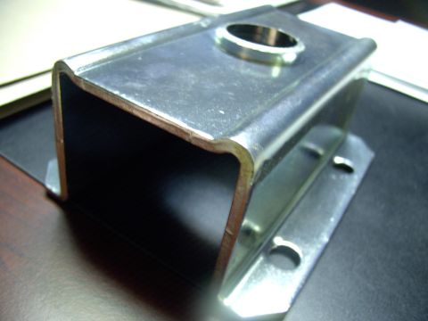 1983 Chrysler Fifth Avenue - A close-up view of a metal bracket, likely a vehicle part, with a circular opening and mounting holes visible.