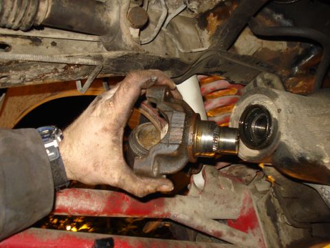 1985 Ford Bronco - Close-up of a mechanic's hands manipulating a U-joint assembly during vehicle maintenance.