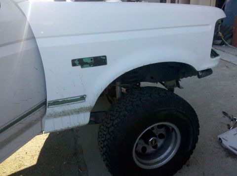 1995 Ford Bronco - Front fender and wheel of a white 1995 Ford Bronco during a strip-down process.