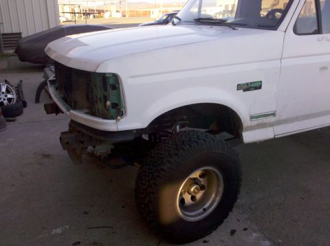 1995 Ford Bronco - Front view of a white 1995 Ford Bronco undergoing a strip down, with the grille and bumper removed.