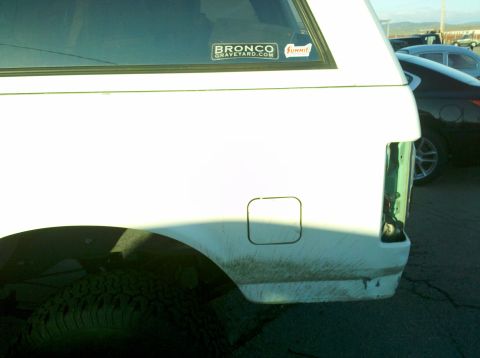 1995 Ford Bronco - Rear view of a white 1995 Ford Bronco showing the quarter panel and a "BRONCOGRAVEYARD.COM" sticker.