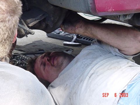 1989 Ford Bronco - Mechanics perform maintenance on the undercarriage of a vehicle.