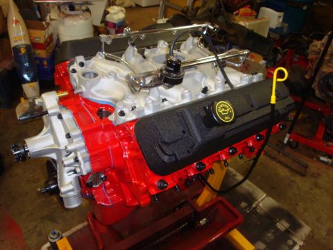 1989 Ford Bronco - Engine assembly with red block and black valve cover, resting on a yellow stand.