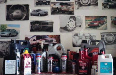 1999 Mercury Grand Marquis - Collection of car photos and automotive fluids displayed on a wall.