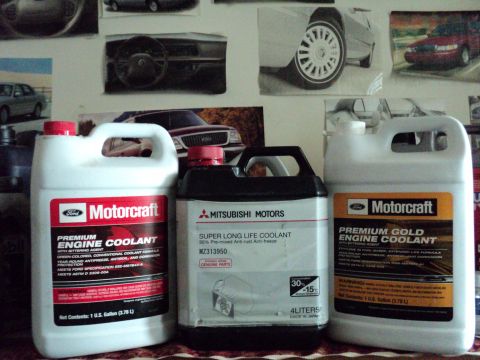 1999 Mercury Grand Marquis - Three different brands of engine coolant are displayed, with automotive-themed posters in the background.