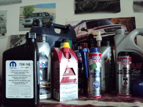1999 Mercury Grand Marquis - A collection of motor oil and cleaning fluids are displayed with posters of vehicles in the background.