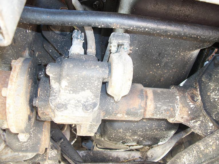 Dusty undercarriage close-up of an axle housing, bracket and brake backing plate