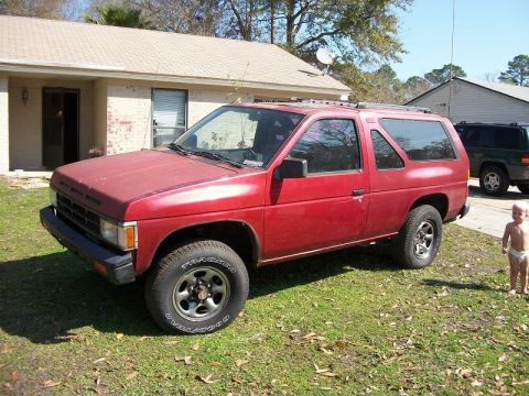 1994 Ford Explorer - A red SUV is parked on a grassy lawn in front of a house, with a child standing nearby.