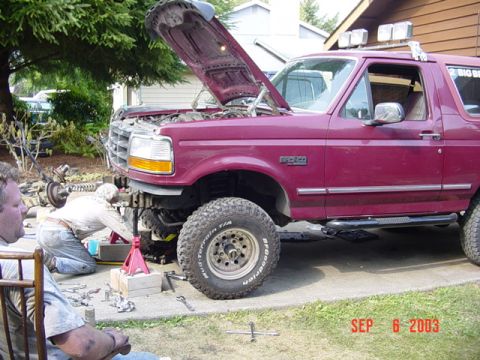 1989 Ford Bronco - A maroon 1989 Ford Bronco is shown with its hood open as mechanics work on the front end, with a date stamp of September 6, 2003.