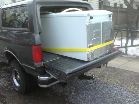1988 Ford Bronco - A dark gray Ford Bronco is used to transport a white chest freezer.