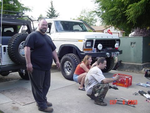 1989 Ford Bronco - A white Ford Bronco from the late 1970s is parked next to a Jeep, with three people nearby.