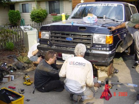 1989 Ford Bronco - A group of people are gathered around a Ford Bronco, appearing to be in the middle of repairs or maintenance.
