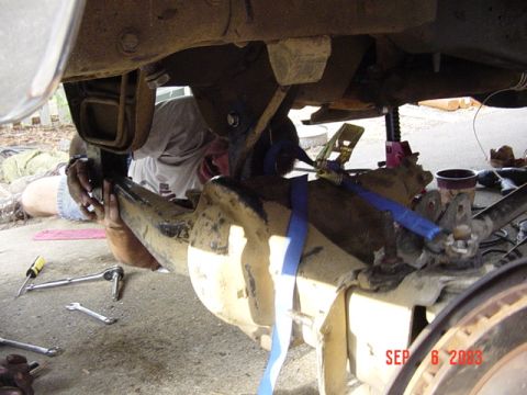 1989 Ford Bronco - A person works on the suspension of a vehicle, with tools scattered around and a date stamp visible on the image.