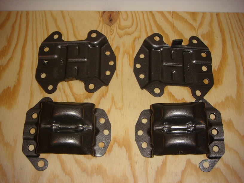 Four dark metal engine mounts on a wood surface