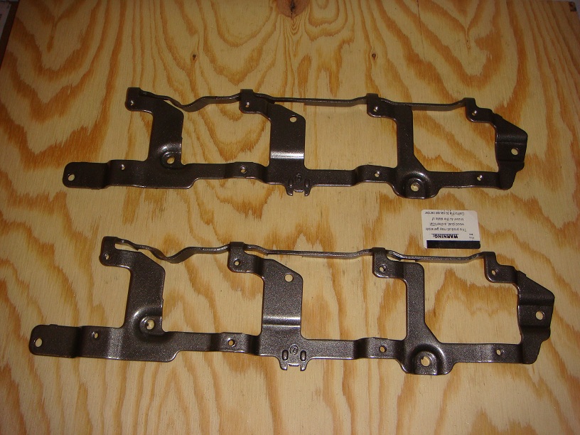 Two metal engine brackets on a wooden surface