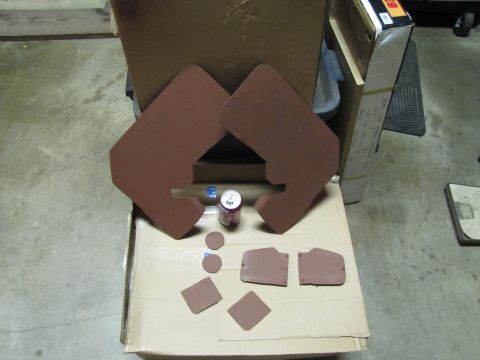 1993 Ford F-250 - Several brown automotive interior trim pieces and a soda can are arranged on a cardboard box in a garage setting.