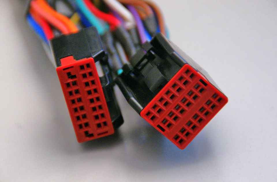 Two red plastic wiring harness connectors with many wires behind them