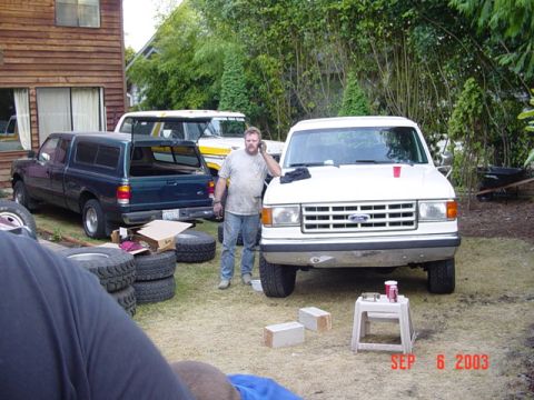 1989 Ford Bronco - White Ford van and dark green Ford Ranger pickup truck parked in a yard with a man standing between them.