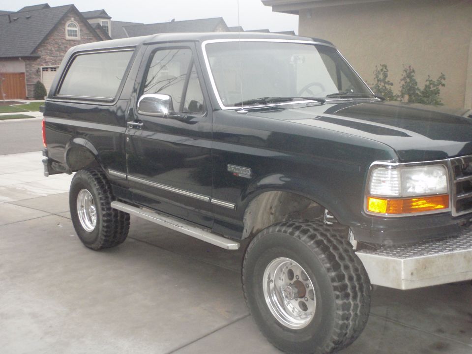 Dark green SUV parked in a driveway. It has chrome trim and aftermarket wheels
