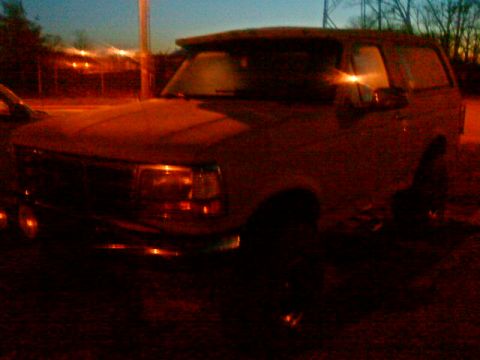 1995 Ford Bronco - The front end of a Ford Bronco is visible in this dimly lit outdoor shot.