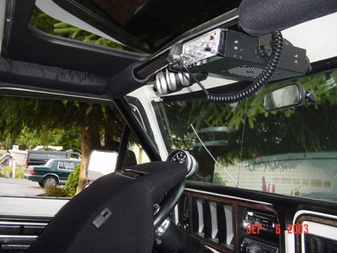 1989 Ford Bronco - The interior of a vehicle shows a CB radio mounted to the overhead console and an aftermarket gauge on the dashboard.